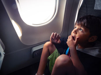 Boy looking away through airplane window