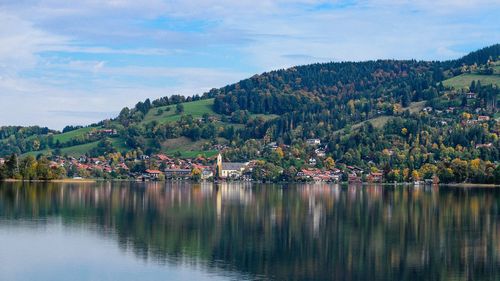 Scenic view of lake by townscape against sky