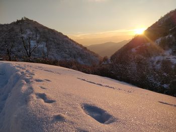 Scenic view of snow covered mountains against sky during sunset