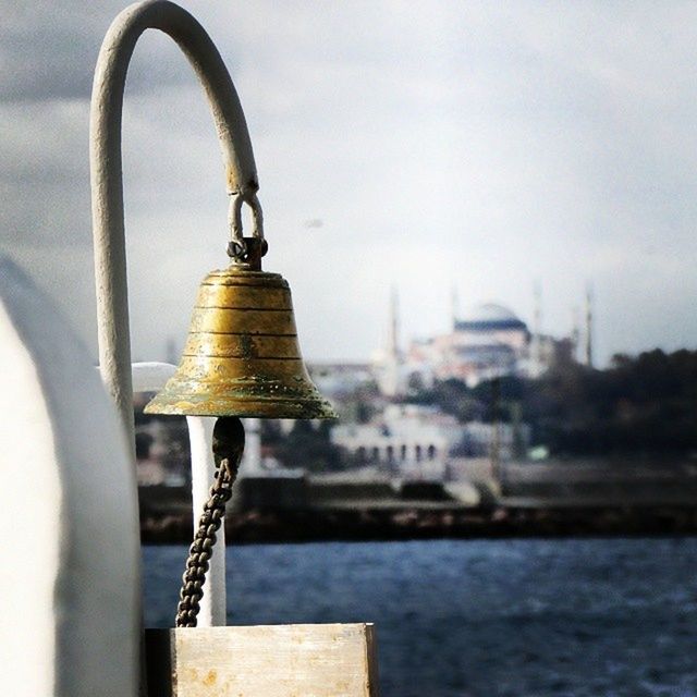 focus on foreground, metal, close-up, water, railing, text, metallic, rusty, padlock, communication, day, sky, selective focus, safety, outdoors, river, no people, sea, western script, protection