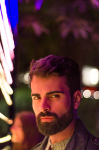 Portrait of young man in city at night