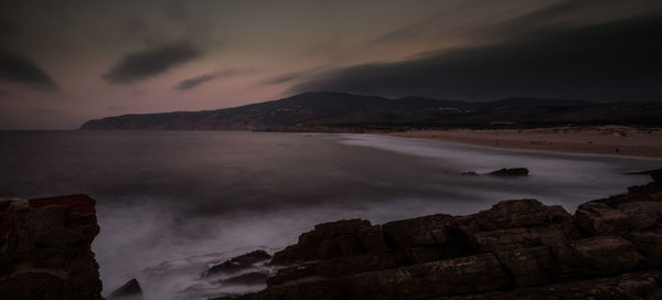 Scenic view of sea and mountains against sky during sunset