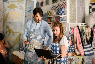 Owners using laptop in fabric shop