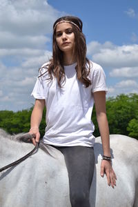 Happy young woman with horse against sky