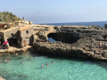 People swimming in sea against sky