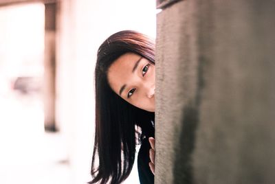 Close-up portrait of young woman standing by wall