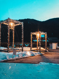 Illuminated swimming pool against blue sky at night