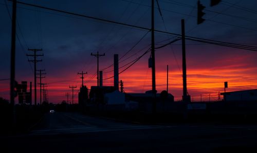 Power lines against cloudy sky at sunset