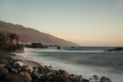 Scenic view of sea and mountains against sky at sunset