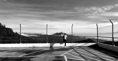 Rear view of man playing soccer on field against sky