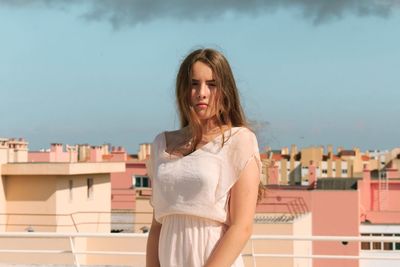 Portrait of smiling young woman standing against sky