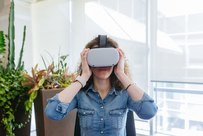 Sitting woman with curly hair trying vr helmet in the office