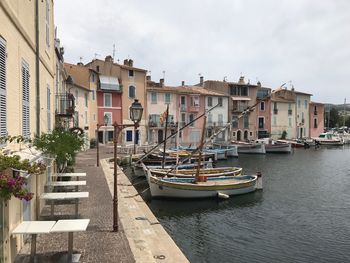 Sailboats moored on canal by buildings in city against sky