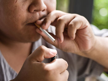 Close-up of man liting cigarette at home