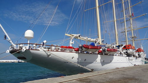 Sailboats moored in sea against sky