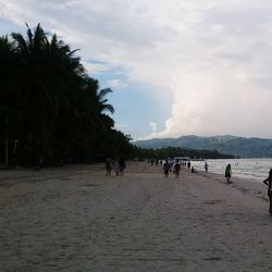 People at beach in front of mountains against sky