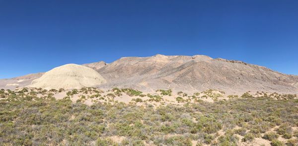 Scenic view of arid landscape against clear blue sky