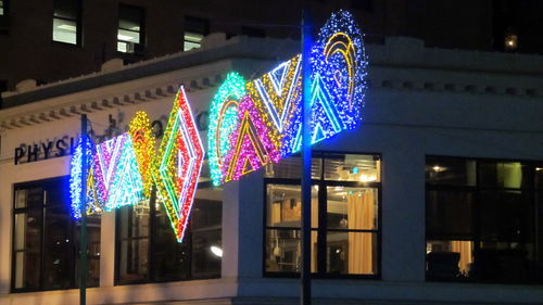 Illuminated christmas lights hanging on building at night