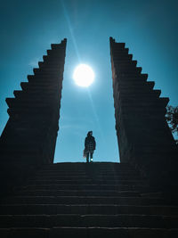 Low angle view of silhouette person standing on staircase against sky