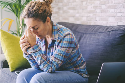 Sad woman sitting on sofa at home