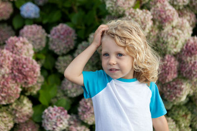 Cute girl looking away while standing against plants