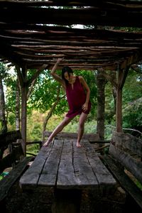 Full length of woman standing on picnic table against trees