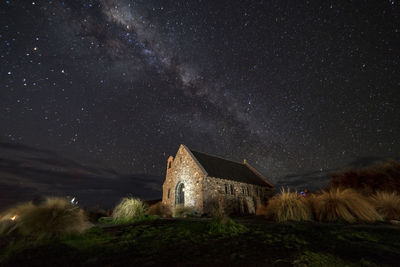 House on land against star field at night