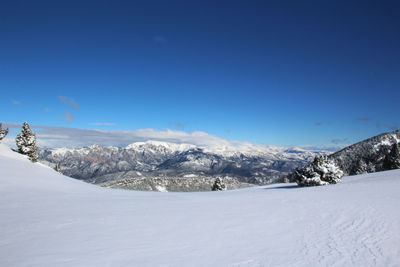 Scenic view of snow mountains against blue sky