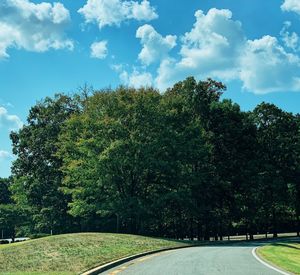 Road amidst trees against sky