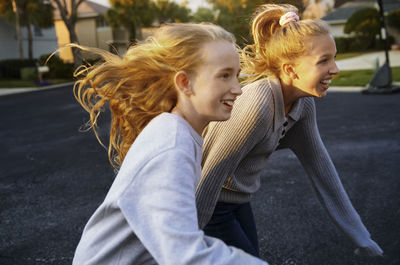 Cheerful girls with blond tousled hair running at suburb area