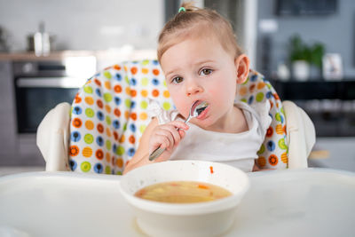 Portrait of cute girl eating food while sitting at home