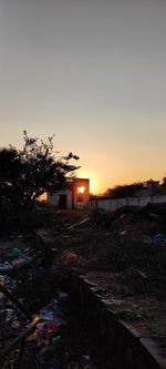 Abandoned house on field against sky during sunset