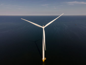 Wind turbines in sea against sky