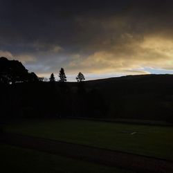 Silhouette field against sky at dusk