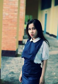 Beautiful young woman standing against blue wall