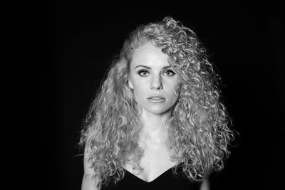 Portrait of woman with curly hair against black background