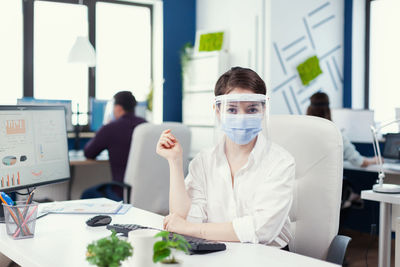 Portrait of young woman using mobile phone in office