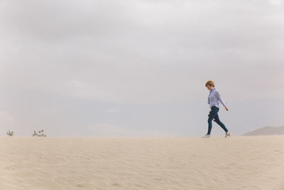 Woman walking on sand dune in desert