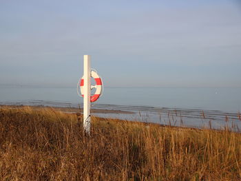 Lifeguard hut on field by sea against sky