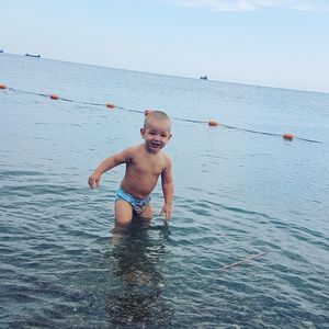 Portrait of happy boy in sea against sky