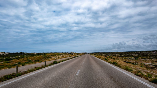 Road amidst field against sky