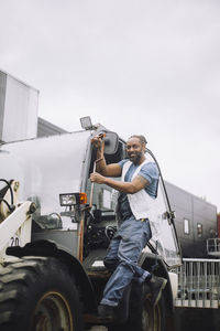 Full length of construction worker standing at doorway of vehicle