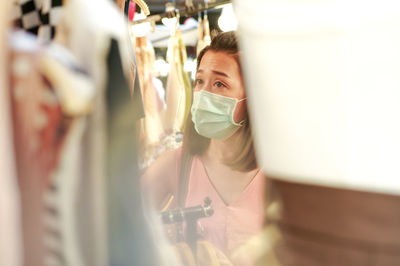 Closeup woman with mask on her face selecting the clothes in the shop. shopping on covid 19 pandemic