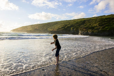 Woman standing on beach against sky