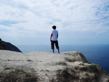 Rear view of man looking at sea against sky