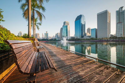 Modern buildings by lake against sky in city