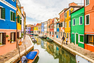 Canal amidst buildings in city against sky