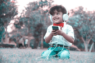 Portrait of boy holding mobile phone on field