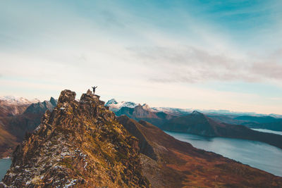 Man on mountain peak against sky