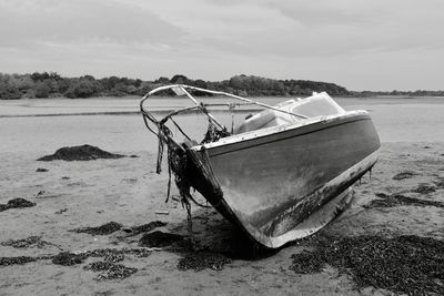 Boat moored on beach against sky